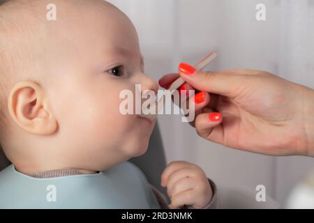 The first feeding with fruit puree for a baby boy who is 6 months old. Stock Photo