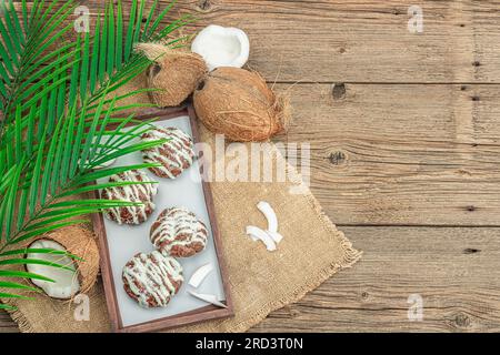 Profiteroles choux pastry buns with coconut cream served in tropical style. Palm leaves, sweet healthy dessert, flat lay, top view Stock Photo