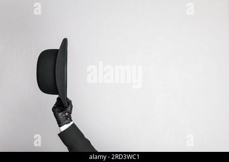 Isolated Image of Leather Gloved Hand Politely Doffing Bowler Hat. Classic British Butler or British Businessman. Copy Space for Service Industry. Stock Photo