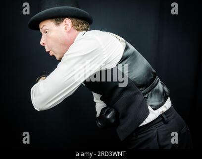 Portrait of Man in Vest and Bowler Hat Comically Punching Himself in the Stomach. Vintage Boxer or Back Alley Ruffian. Stock Photo