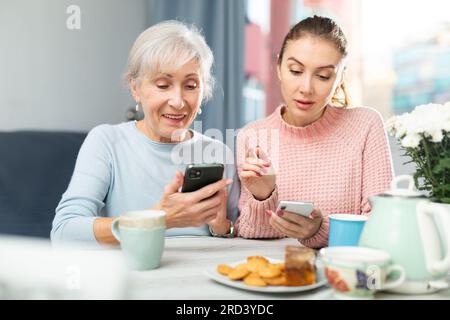 Senior woman and her granddaughter using smartphones at home Stock Photo