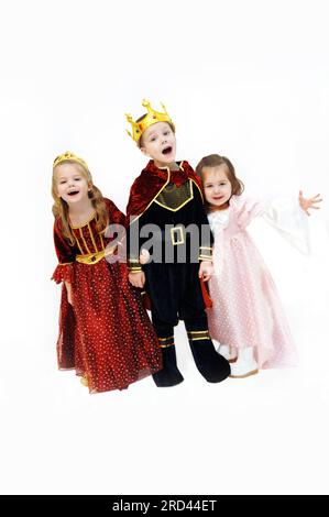 King, queen and princess are laughing and talking as they pose in their Halloween costumes.  Children are wearing crowns, gowns and royal cape. Stock Photo