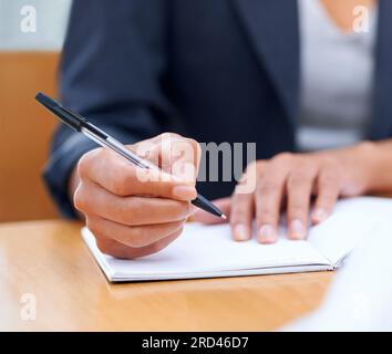Putting pen to paper...Closeup image of a businesswoman writing in a notebook. Stock Photo
