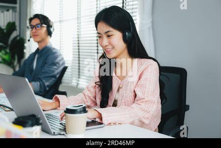 Happy customer service operator with headsets working at call centre, Call center agent with headsets working on support hotline in modern office Stock Photo