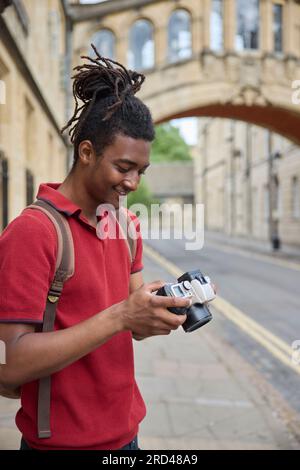 Young Man Travelling On Vacation Taking Photo With Camera When Sightseeing In Oxford Stock Photo