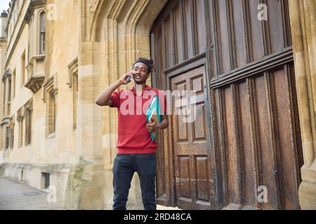 Male Student Making Call On Mobile Phone Outside University Building In Oxford UK Stock Photo