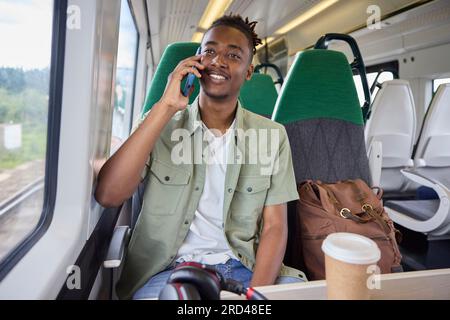 Young Man Commuting To Work On Train Sitting  On Train Talking On Mobile Phone Stock Photo