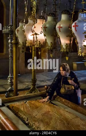 Woman touching devoutly the Stone of Anointing in the Church of the Holy Sepulchre in the Christian Quarter of the Old City of Jerusalem Stock Photo