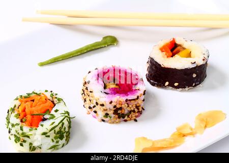 Vegan sushi rolls and a pair of chopsticks on a white plate Stock Photo