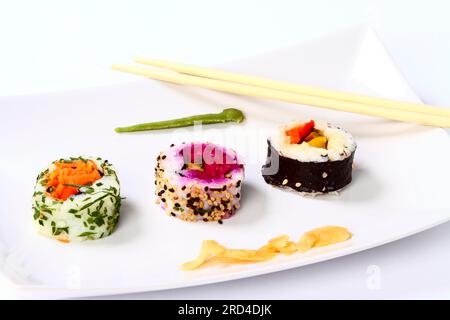 Vegan sushi rolls and a pair of chopsticks on a white plate Stock Photo