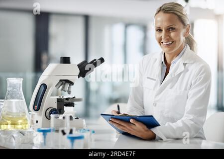 Im here to cure. Cropped portrait of an attractive mature female scientist taking down notes while doing research in her lab. Stock Photo