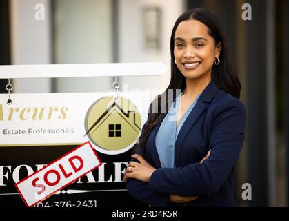 Sold, real estate and woman in portrait with arms crossed for home investment, property sale and agency. Happy face of agent, realtor or biracial Stock Photo