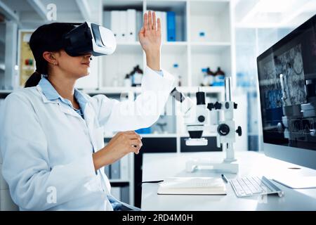 Woman, scientist and VR goggles with computer screen, science innovation in lab and futuristic tech with metaverse. Virtual reality, digital data and Stock Photo