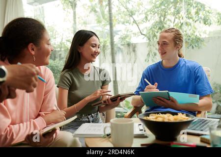 Group of joyful college students brainstorming ideas for mobile application Stock Photo