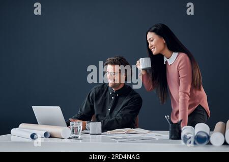 How do you like the look of that. Shot of two young architects going over designs on a laptop together in their office. Stock Photo