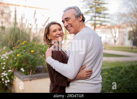 Romantic Mature Spouses Embracing Smiling At Camera In Park Outside Stock Photo
