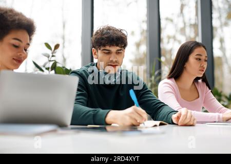 Study process concept. Multiracial students sitting at desk learning together, preparing for university exams Stock Photo