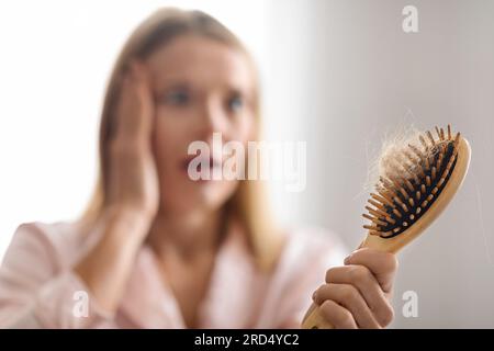Hairloss Problem. Shocked Mature Woman Looking At Comb Full Of Fallen Hair Stock Photo