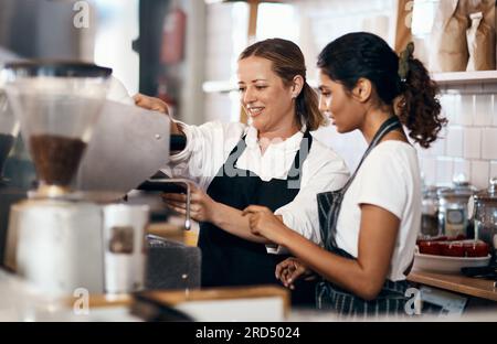 The skill behind the coffee that you love so much. Shot of two women preparing coffee in a cafe. Stock Photo