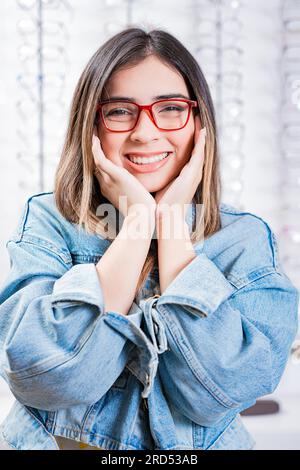 Happy female customer modeling glasses in an optical store. Happy teen girl in eyeglasses on a background of optical store Stock Photo