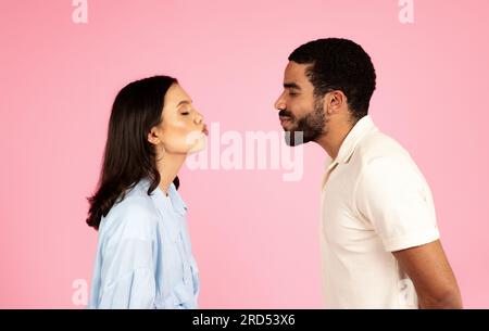 Romantic millennial couple reaching each other with kissing lips Stock Photo