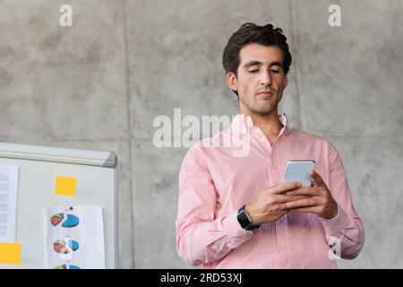 Concentrated young entrepreneur working at office, using smatphone Stock Photo