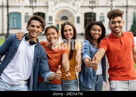 We Like Learning. Multiethnic Students Gesturing Thumbs Up While Standing Outdoors Stock Photo