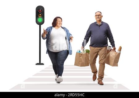 Full length portrait of a young woman crossing a street and talking to a mature man with grocery bags isolated on white background Stock Photo