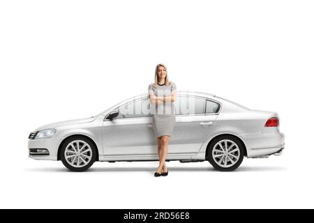 Full length portrait of a young woman leaning on a silver car isolated on white background Stock Photo