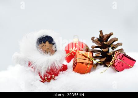 Christmas decoration, Inuit with Christmas tree ball and pine cones and Christmas presents lying in the snow Stock Photo