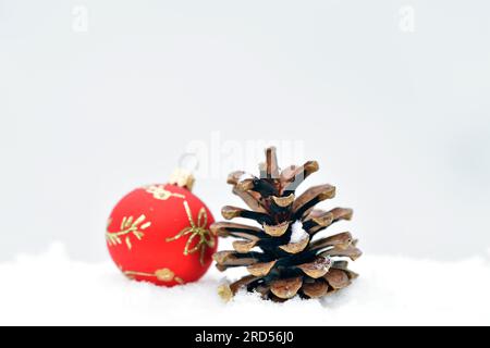 Christmas decoration, Christmas tree ball and pine cones lie in the snow Stock Photo