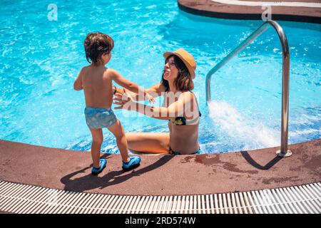 Mother and son in the pool on summer vacation, having fun with their mother Stock Photo