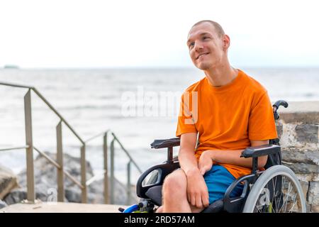 Portrait of a disabled person in a wheelchair at the beach on summer vacation smiling Stock Photo