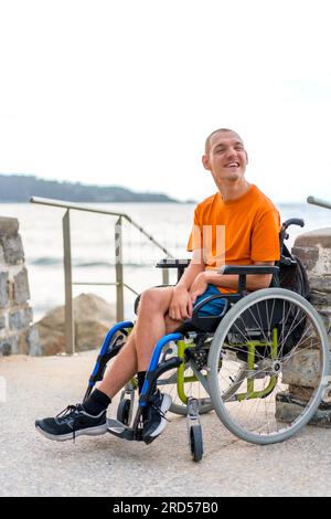 Portrait of pretty cheerful disabled person in wheelchair at the beach on summer vacation smiling Stock Photo