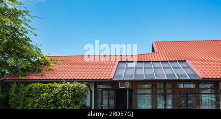 The roof of the house is made of red metal tiles. Tiled Metallic Roof Or Composite Covering On House. appearance of rooftile with terra cotta color Stock Photo