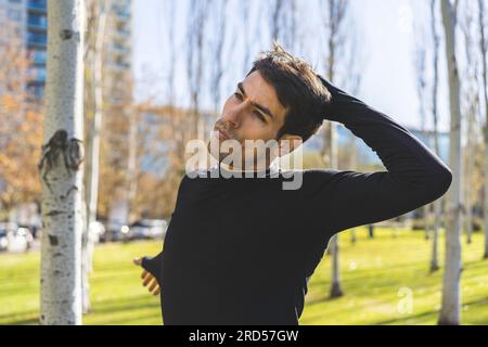Sporty handsome man stretching neck and head after jogging in city public park Stock Photo