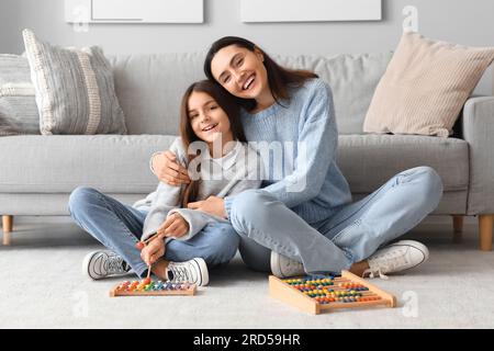 Little girl and her mother in knitted sweaters with toys at home Stock Photo