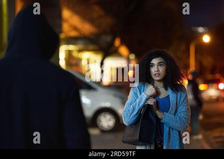 Danger, woman fear and criminal in the city at night with thief and anxiety outdoor, Urban, dark and female person feeling scared with stress and Stock Photo