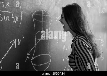 Angry female Math teacher near blackboard in classroom Stock Photo