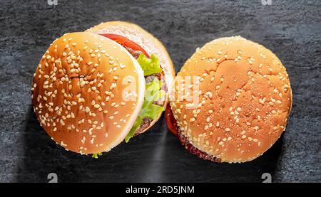 Three Homemade veggie burgers with sweet potato, black rice and red beans, served on wooden chopping board over old wooden table. Rustic style. Flat l Stock Photo