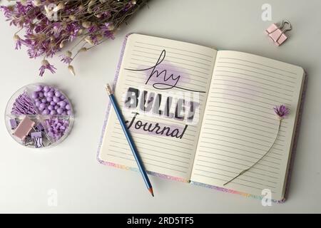 Improve your productivity. Notebook with words My bullet journal, stationery and flowers on white table, flat lay Stock Photo