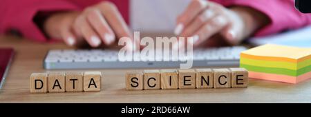 Words data science on wooden cubes and female scientist working with data on computer. Stock Photo