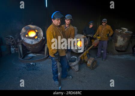 Foundry workers casting molten metal in a small family run foundry in Perth, Western Australia Stock Photo