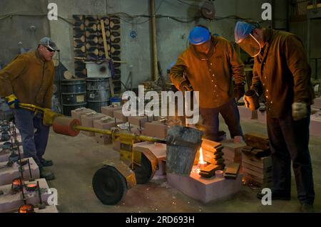 Foundry workers casting molten metal in a small family run foundry in Perth, Western Australia Stock Photo