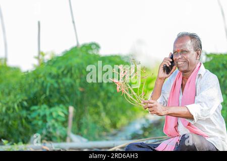 happy farmer siting in soil talking on phone , old indian farmer Stock Photo