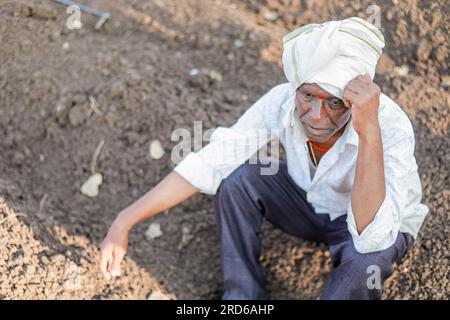 sad farmer, Elderly farmer man sitting in the soil & lost in thought ...