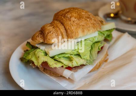 Delicious Italian corissant bread with cold cuts, cheese and salad served with coffee in restaurant Stock Photo