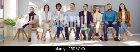 Company employees pose for publicity photo in open poses. Women sit cross-legged Stock Photo