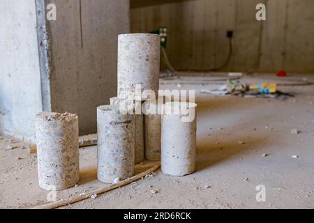 A few concrete cylindrical pillars placed on the floor of building under construction drilled for quality testing. Stock Photo