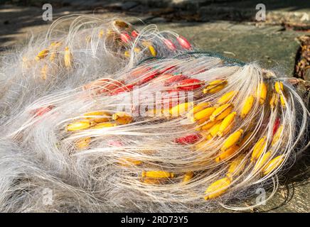 Inshore fishing nets with colourful red and yellow floats laid out in front of trees on on South Beach, Son Tra, Danang, Vietnam Stock Photo